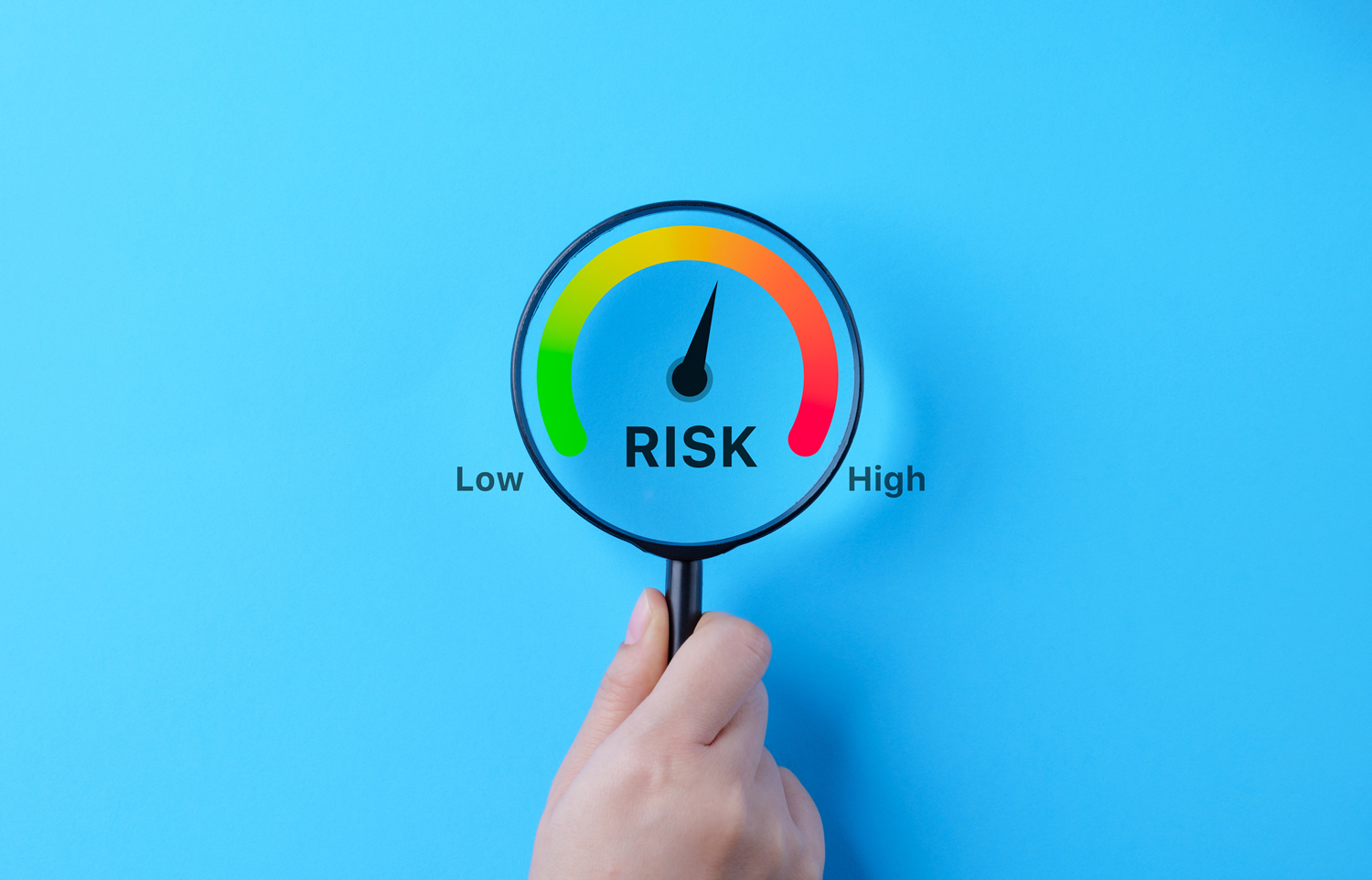 Hand hält Lupe, die das Wort Risk vergrößert